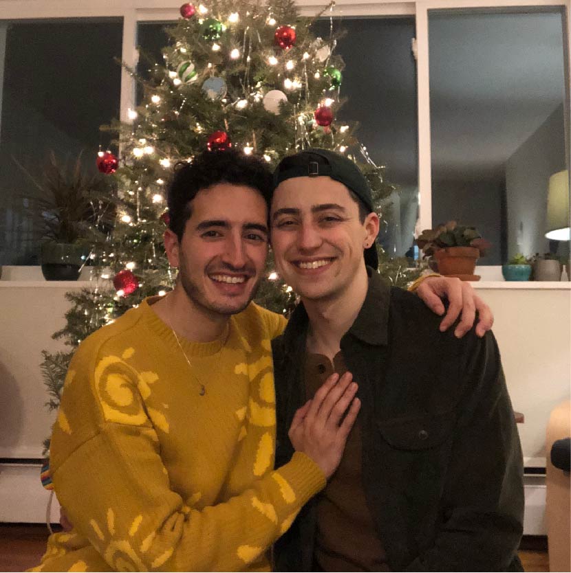 Darius and Tom sitting in front of a Christmas tree